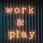 lit up sign on wall that says "Work & Play"