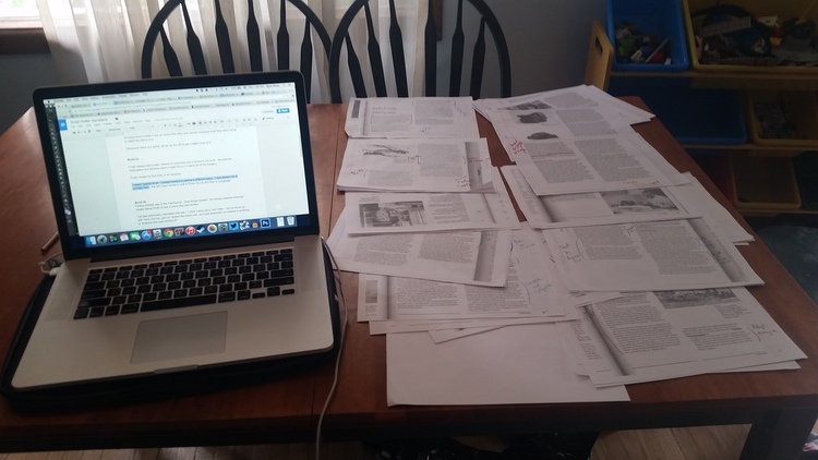 a laptop open with google docs and papers on a table