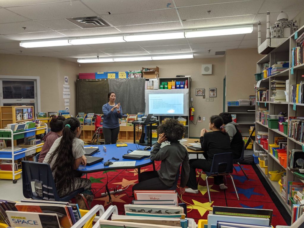 Delivery team Courtney teaching a group of students at a couple desks