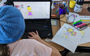A student creating digital pixel art of a person based on a drawing.