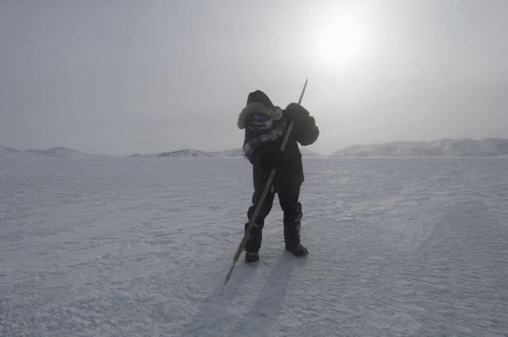 Noah Noggasak demonstrates traditional use of a harpoon to gauge sea ice safety.
