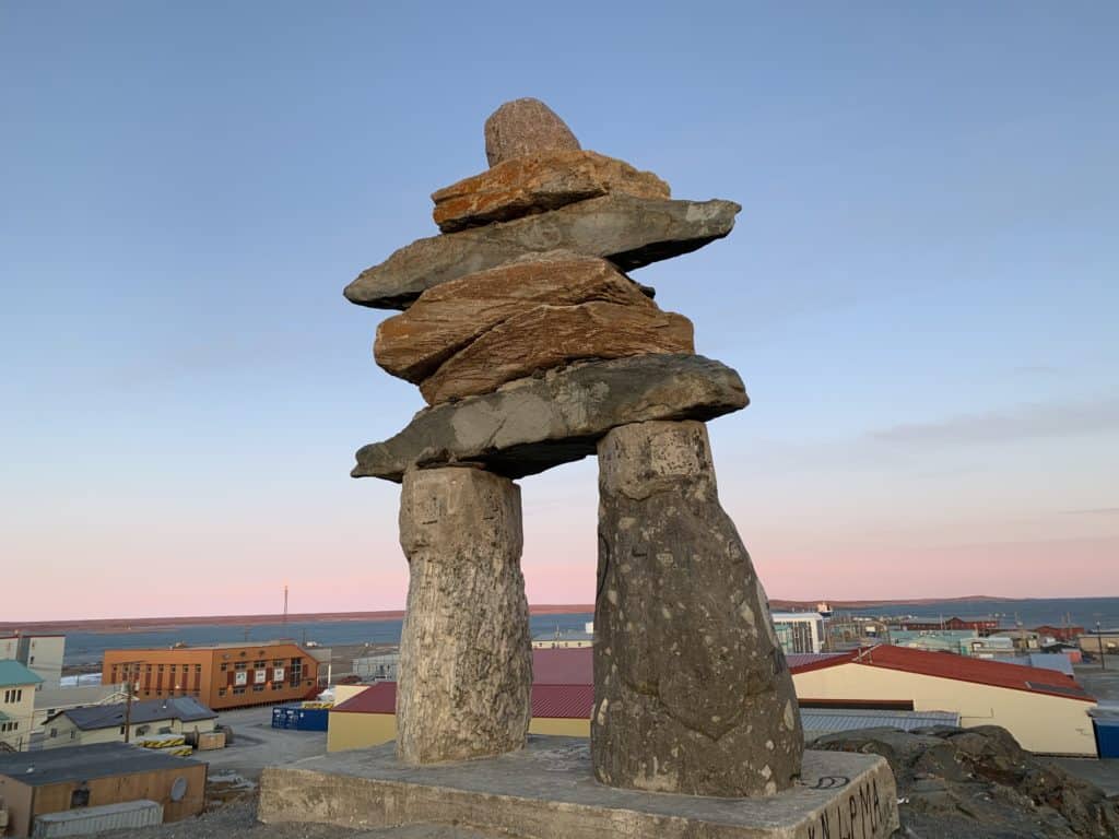 Inuit Inuksuk, over looking the view of a town.