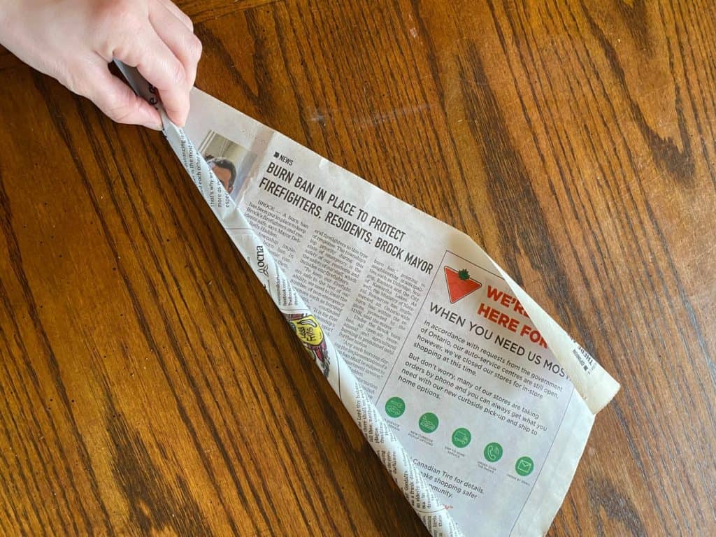 A single sheet of newspaper being tightly rolled.
