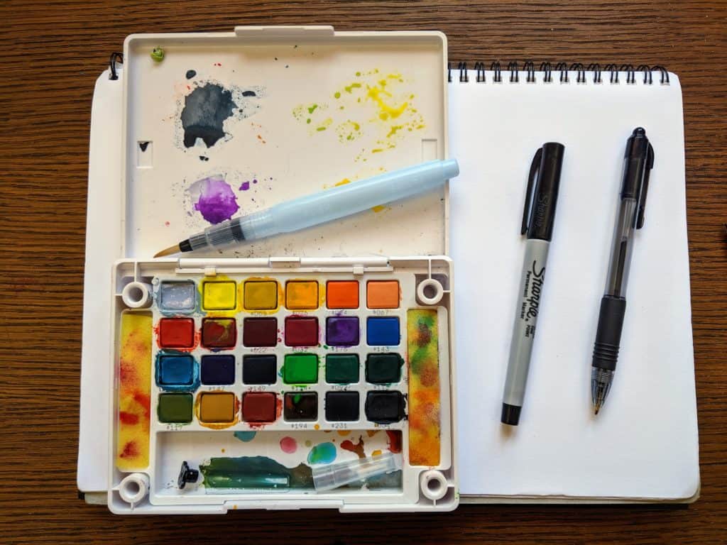 A blank piece of paper with a watercolor paint set and brush.