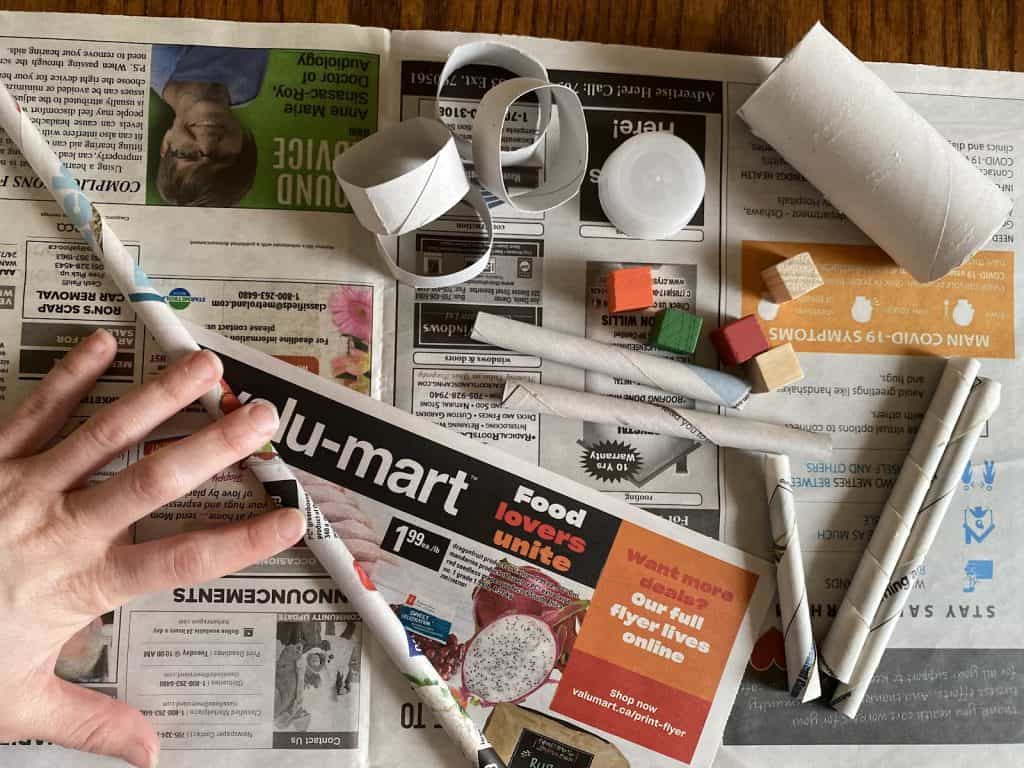 Materials laid out on newspaper with a person rolling up a piece of newspaper.