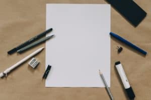 A blank piece of paper with writing utensils beside it.