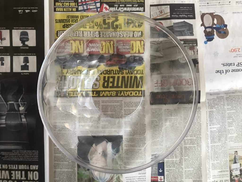 A clear, empty bowl sitting on newspaper.