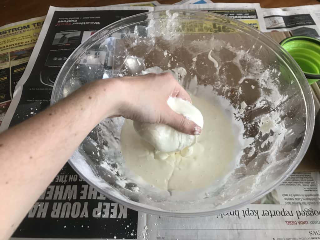 Hands mixing cornstarch and water.