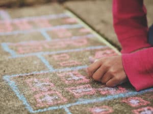 A kid drawing with chalk on pavement.