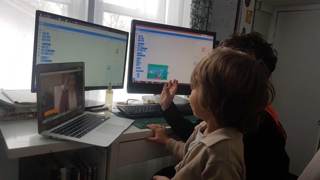 2 learners sitting in front of double monitors, with Google meetings opened on a separate laptop.