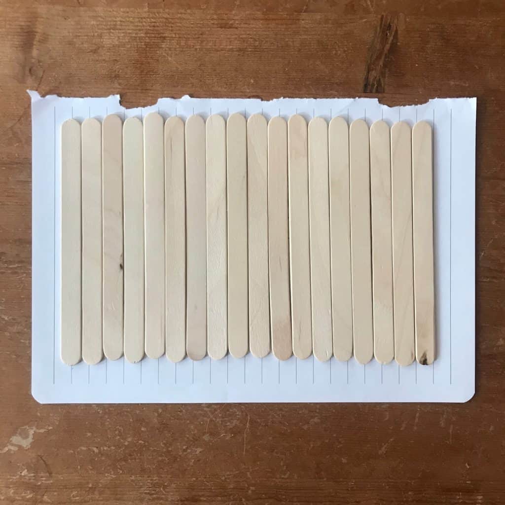 Popsicle sticks lined on a piece of paper.